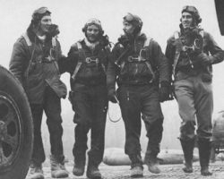 Pilotes du 354th Fighter Group, de retour de mission. De gauche à droite, le capitaine James D. Dalglish, le major Glenn T. Eagleston, le capitaine Orrin D. Rawlings, et le 1er lieutenant J. Loyd Overfield. Les pilotes se rendent sous la tente du débriefing Pilotes du 354th Fighter Group, de retour de mission. De gauche à droite, le capitaine James D. Dalglish, le major Glenn T. Eagleston, le capitaine Orrin D. Rawlings, et le 1er lieutenant J. Loyd Overfield. Les pilotes se rendent sous la tente du débriefing